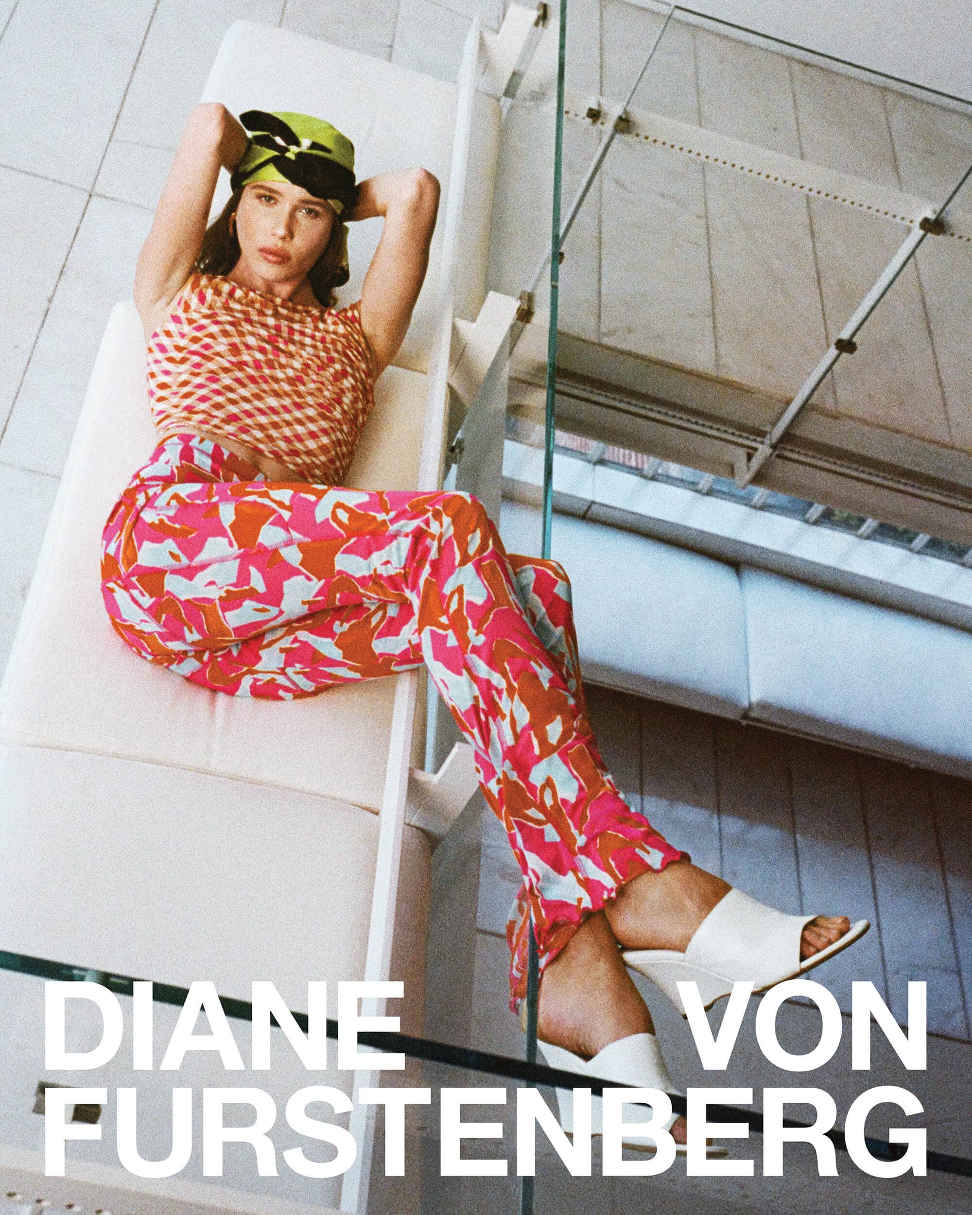 Model wearing patterned pink pants and matching top reclines on a white architectural structure with a lime green head covering.