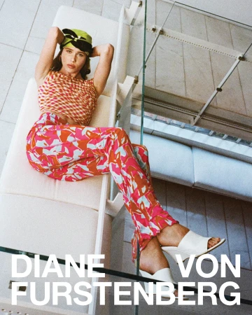 Model wearing patterned pink pants and matching top reclines on a white architectural structure with a lime green head covering.