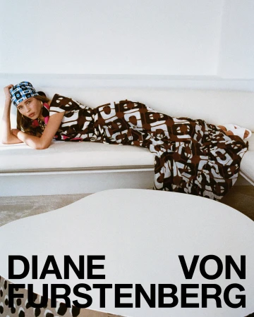 Model lying on a white sofa wearing a patterned brown dress and blue headscarf, photographed for Diane von Furstenberg.