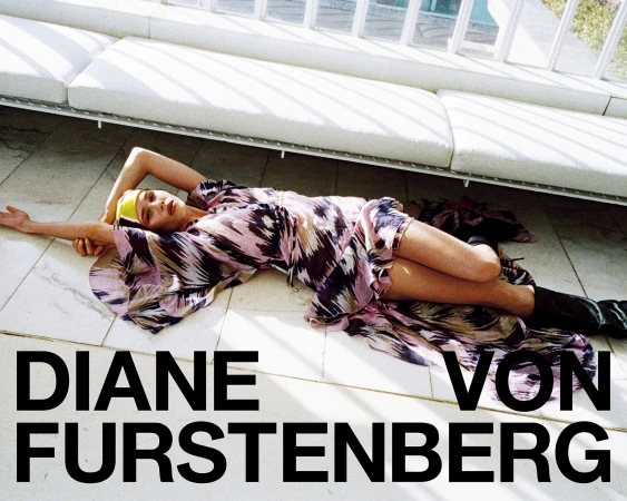 Model lying on tiled floor wearing a patterned dress below a white sofa for Diane von Furstenberg