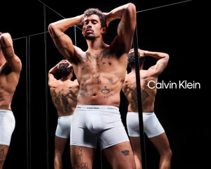 Bad Bunny wearing white Calvin Klein boxer briefs posing in front of multiple reflective mirrors against a dark background