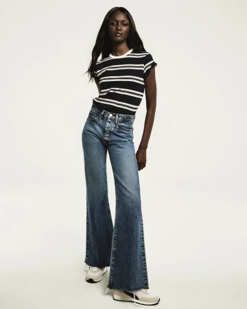 Model wearing a black and white striped t-shirt and denim jeans against a white seamless background for FRAME campaign.