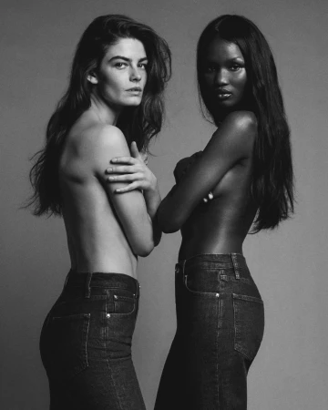 Two female models wearing dark denim jeans posing against a plain grey studio background for FRAME denim spring campaign.