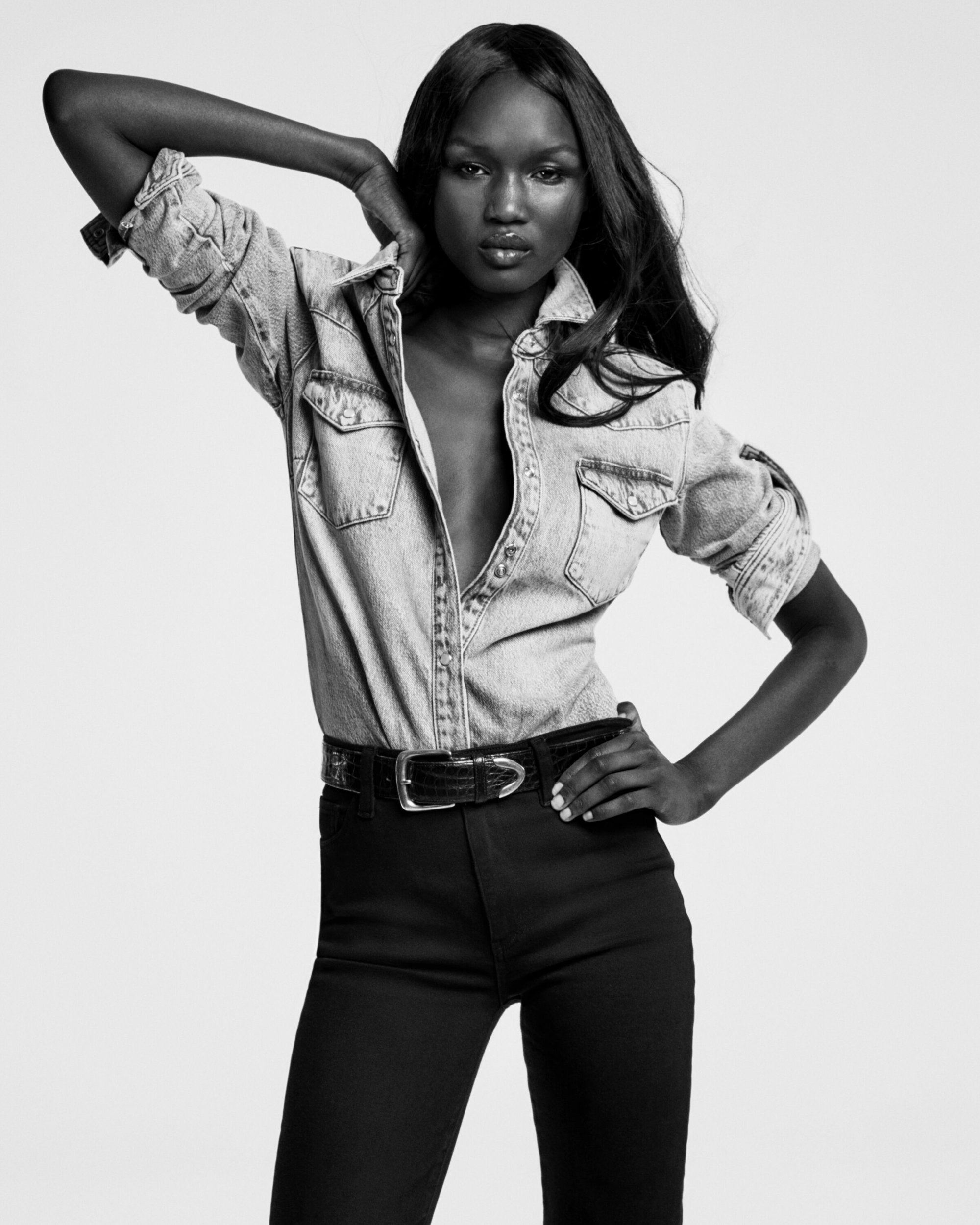 Abény Nhial wearing a denim shirt and dark trousers against a plain background for FRAME