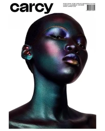 Close-up beauty portrait of a model with iridescent metallic makeup and shaved head against a plain white background for Carcy Magazine.