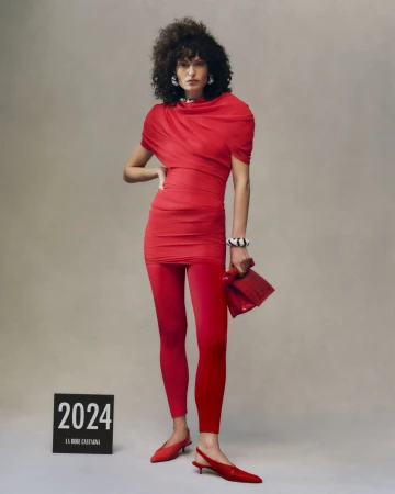 Model in a red dress and leggings holding a matching red handbag against a neutral grey studio background