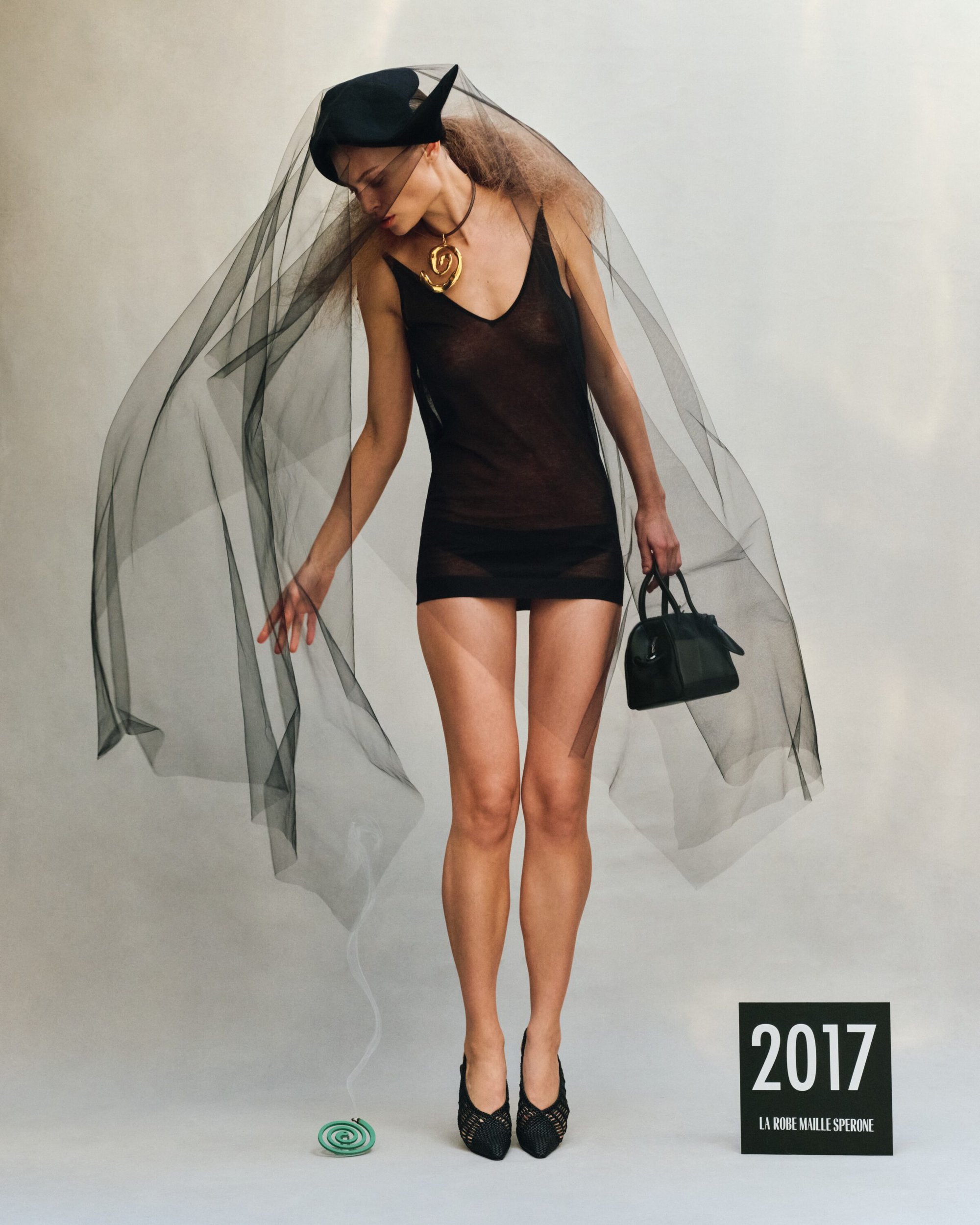 Model in a sheer black slip dress with veil and handbag for the Jacquemus Spring 2025 ad campaign.