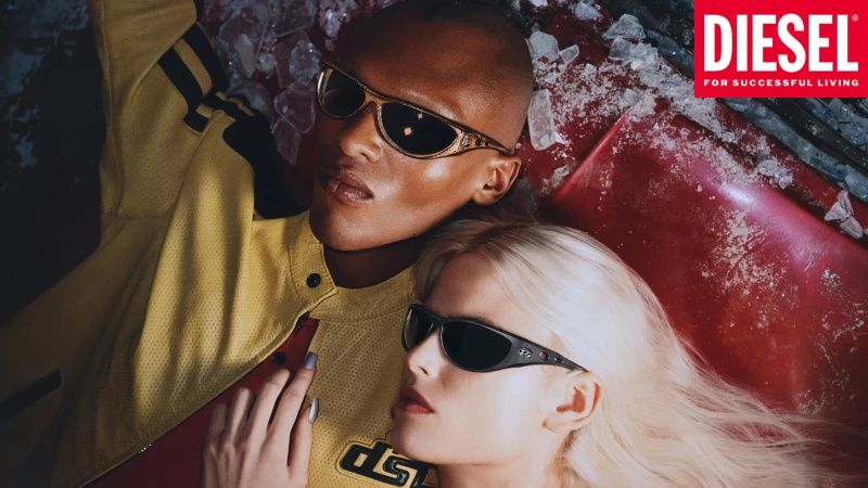 Two models wearing sunglasses reclining near a red vehicle in Diesel The Houseguests campaign shot by Frank Lebon.