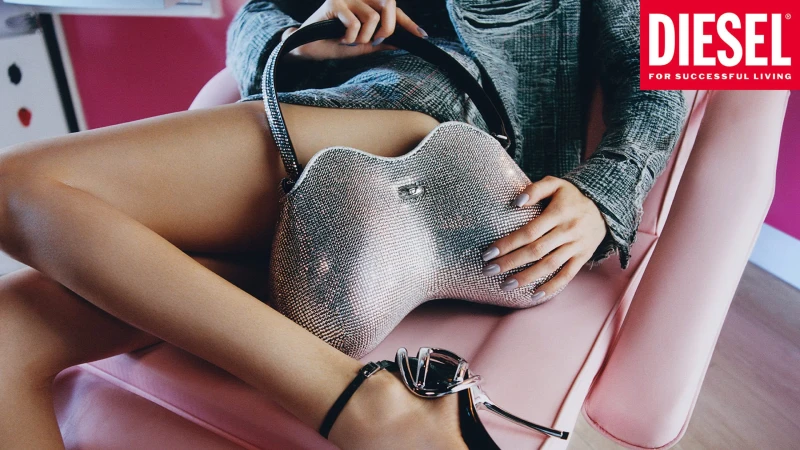 Model seated on a pink chair holding a heavily crystal-embellished handbag for Diesel advertising campaign