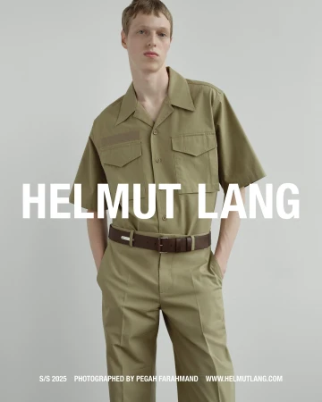 A male model wearing an olive green short-sleeve utility shirt and matching trousers against a plain grey background