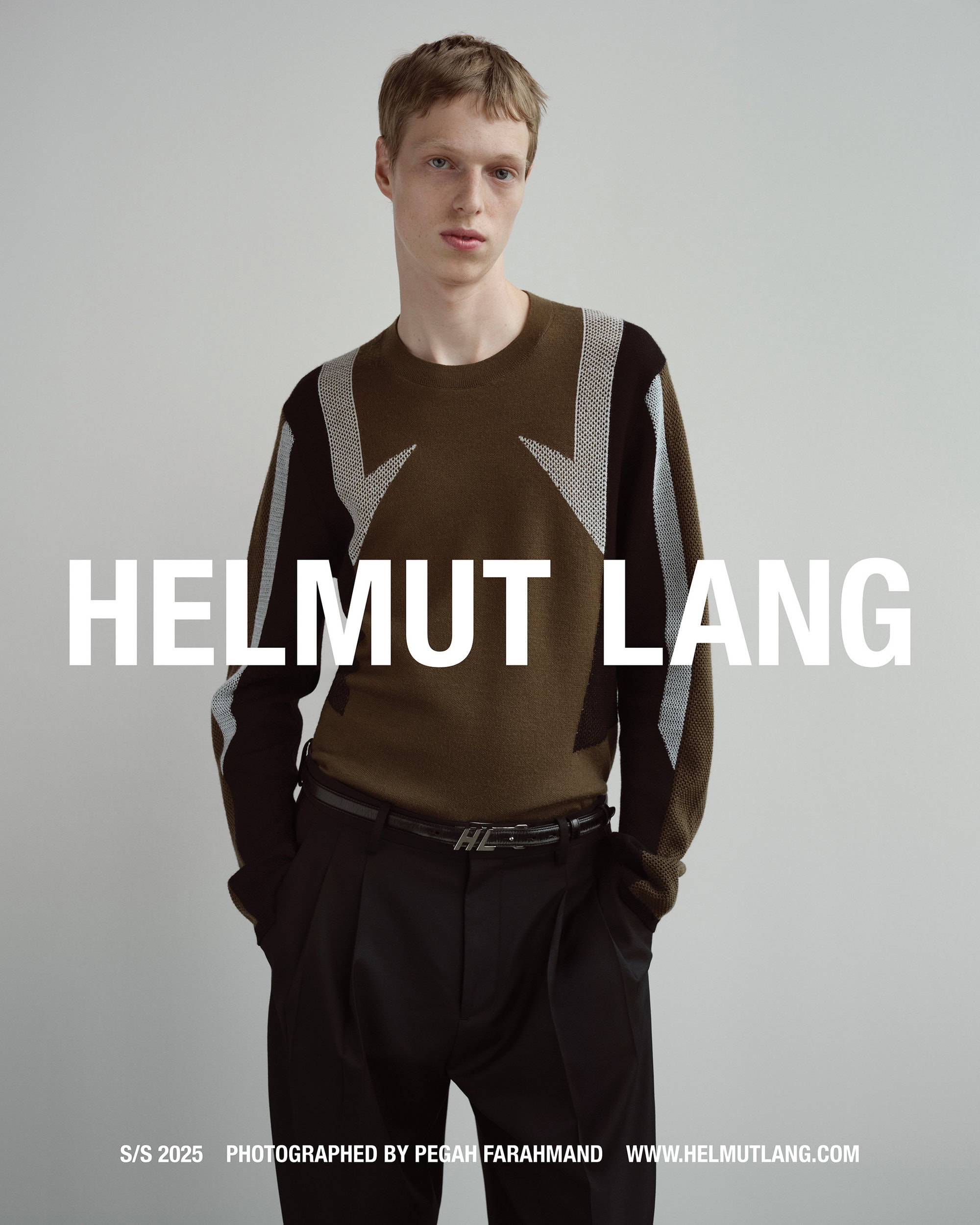 Model wearing a patterned knit sweater and dark trousers against a plain grey studio background with bold white text overlay.