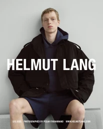 A male model seated wearing a dark jacket and blue hoodie against a light grey studio backdrop with Helmut Lang branding across the center.