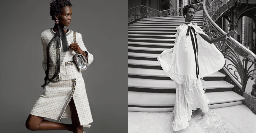 Model wearing a white tweed skirt suit with a black ribbon tie and holding a sequined handbag against a grey studio backdrop.