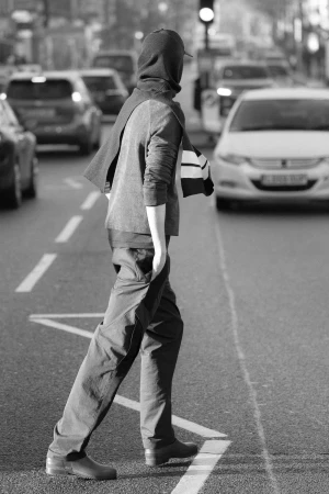 Monochrome street view of a person walking across a city street amidst cars