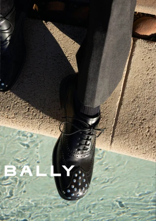 Close-up of black leather oxford dress shoes worn with trousers near an outdoor pool edge