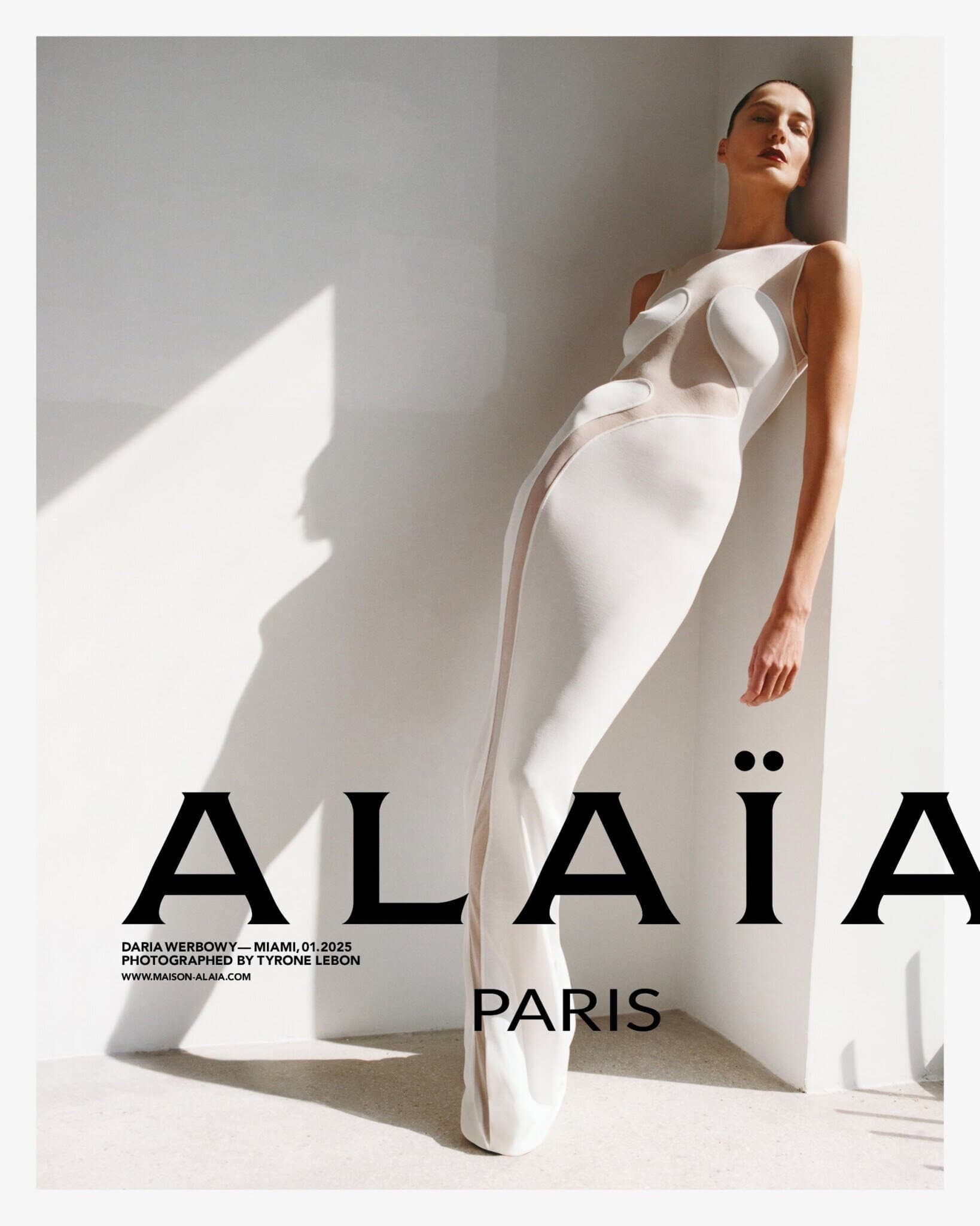 Model Daria Werbowy in a white sleeveless floor-length dress leaning against a wall for Alaia Spring 2025 campaign.
