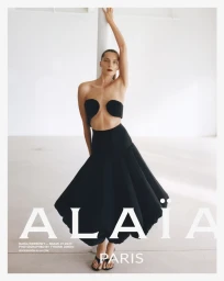 Model Daria Werbowy posing in a black sculptural dress against a white seamless background for the Alaïa Spring 2025 campaign.
