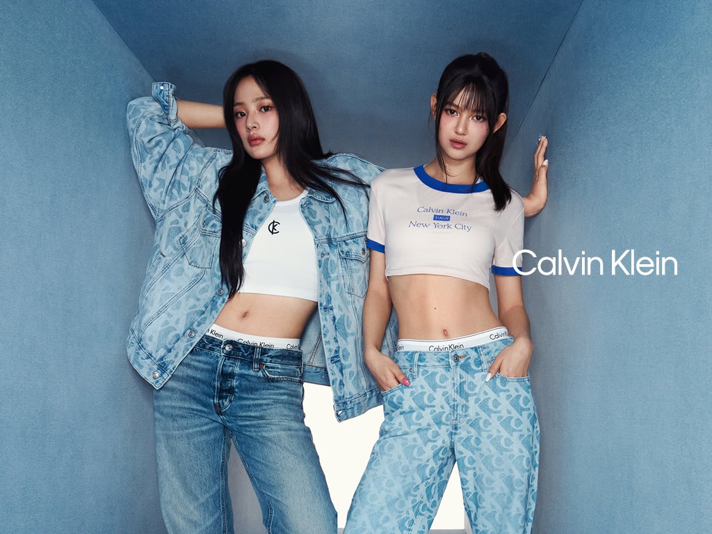 Two models wearing Calvin Klein apparel in a narrow blue tunnel set with a white light background