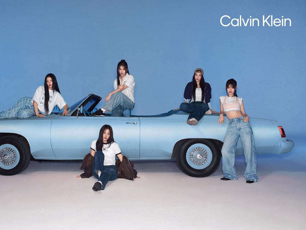Five models posing with a light blue convertible car against a matching blue studio background for Calvin Klein.