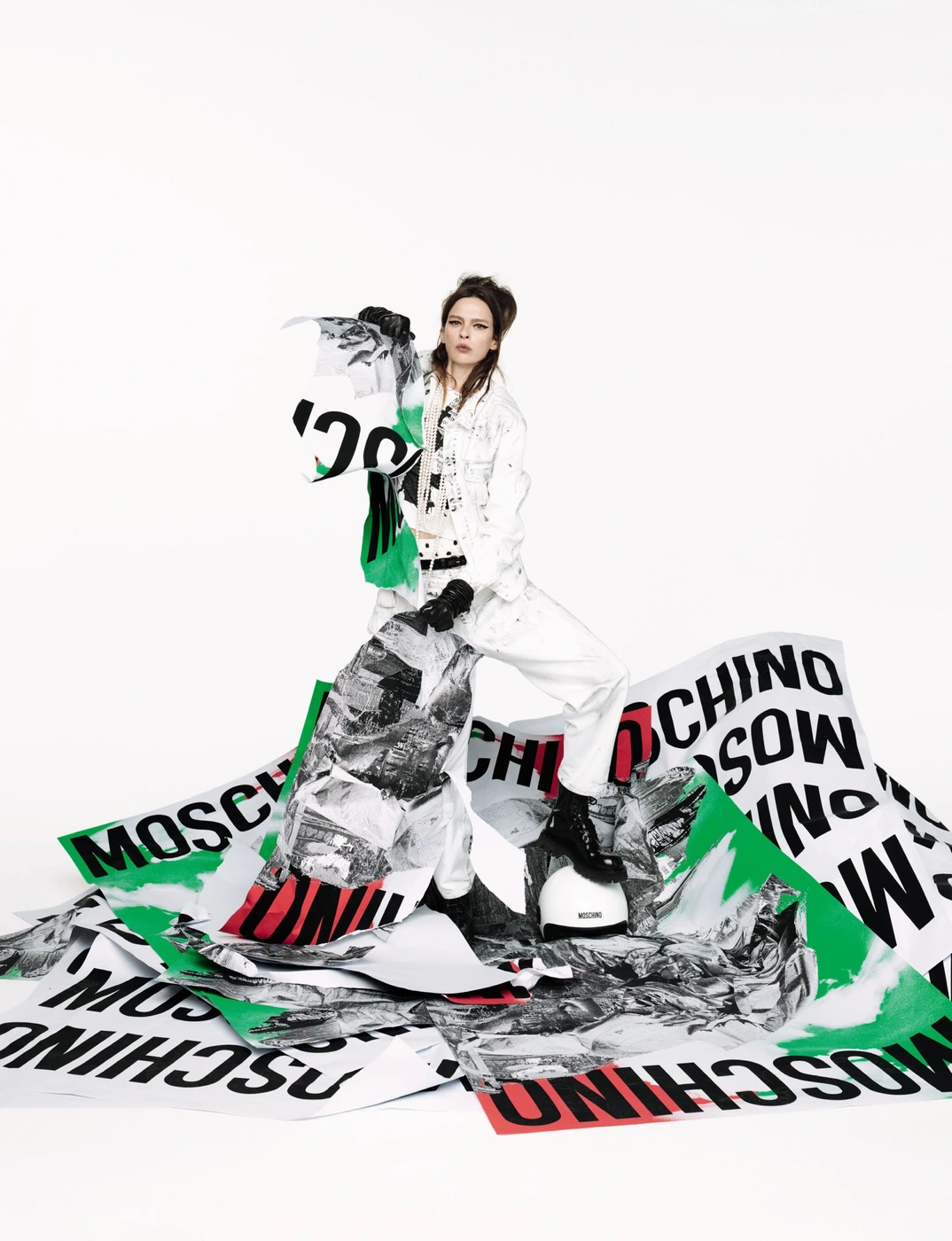 Model standing among large printed posters on white background for Moschino
