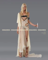 Model with long blonde hair wearing a sheer layered cream dress holding a lit candle against a grey studio backdrop