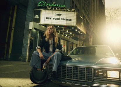Model Lila Moss sitting on the hood of a vintage car outside Cinema Village for DKNY Spring 2025 ad campaign.