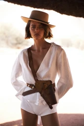 Georgia Fowler wearing a white linen shirt, felt hat, and leather holster for Sir The Label