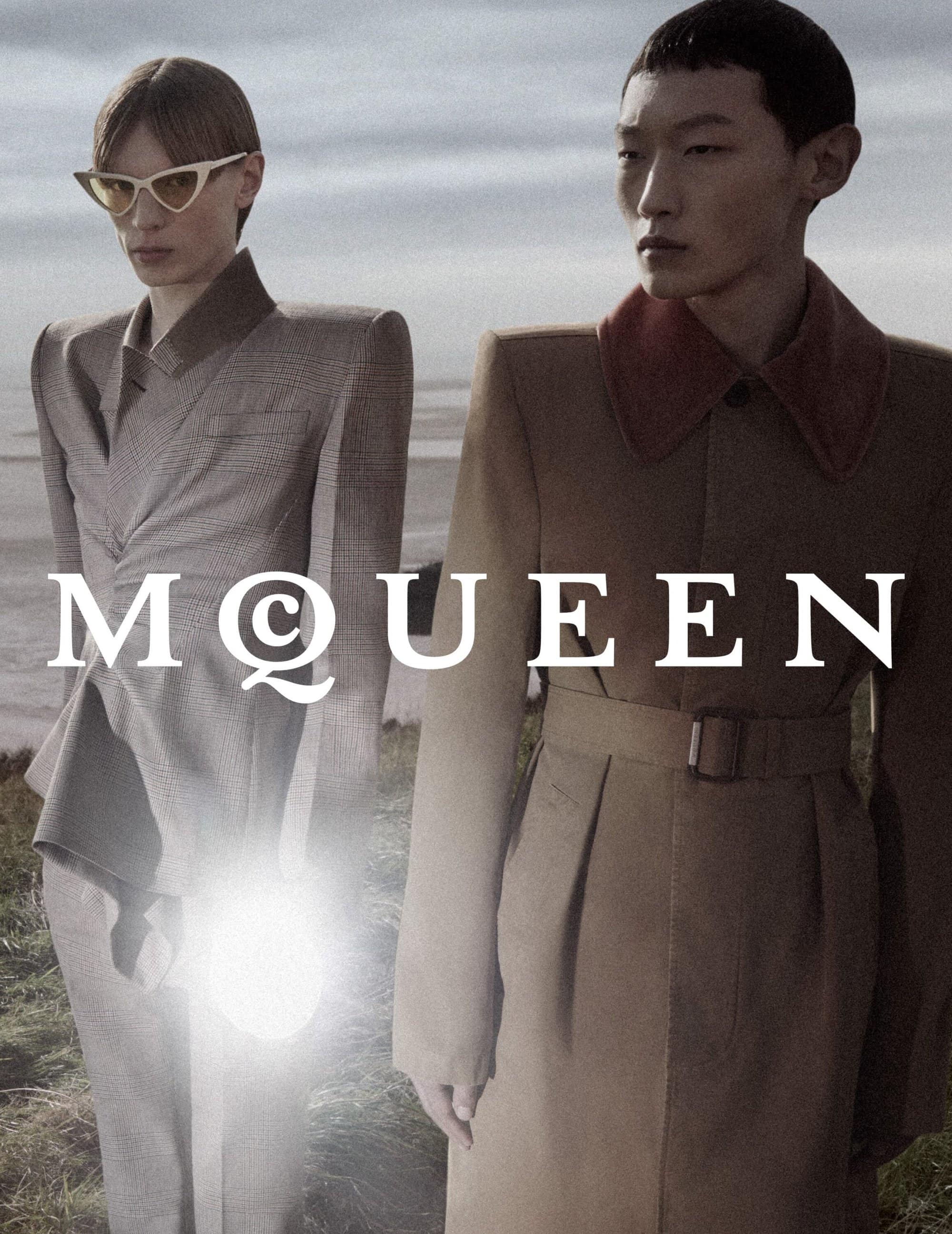 Two fashion models posing outdoors against a pale horizon wearing tailored structured coats for McQueen