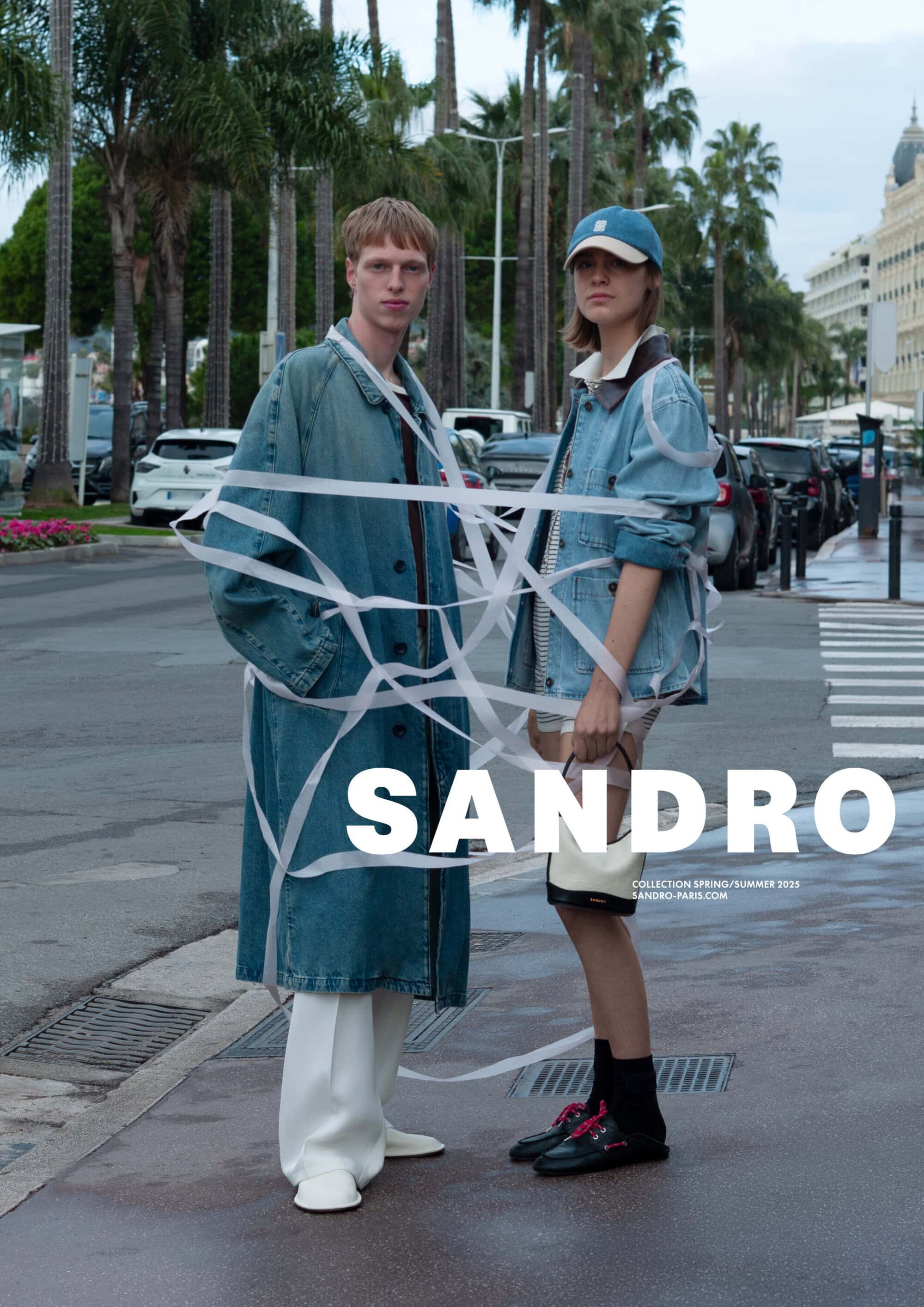 Two models standing on a street wrapped in white ribbons wearing denim coats for Sandro Spring 2025 campaign.
