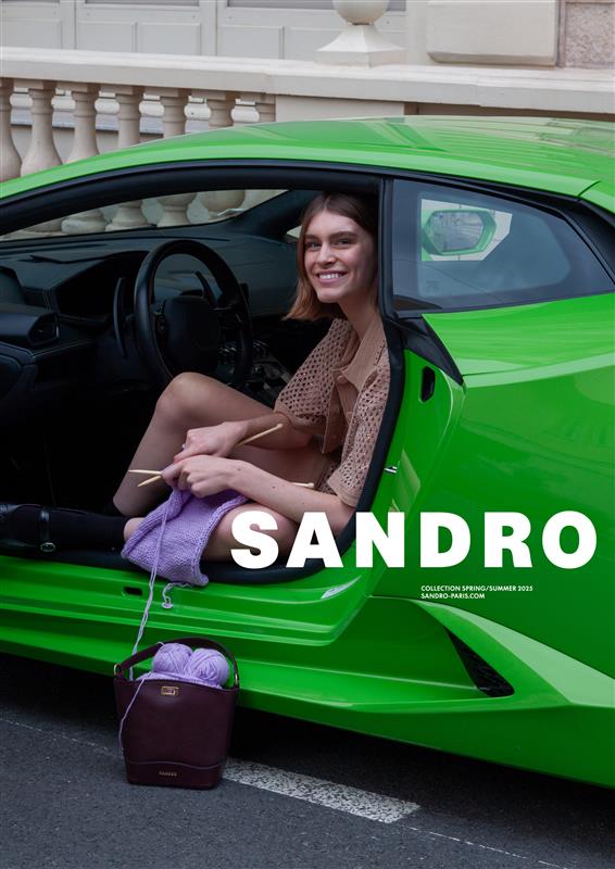 Model sitting in a bright green sports car knitting with purple yarn for Sandro Spring 2025 campaign