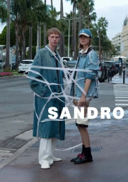 Two models standing on a street wrapped in white ribbons wearing denim coats for Sandro Spring 2025 campaign.