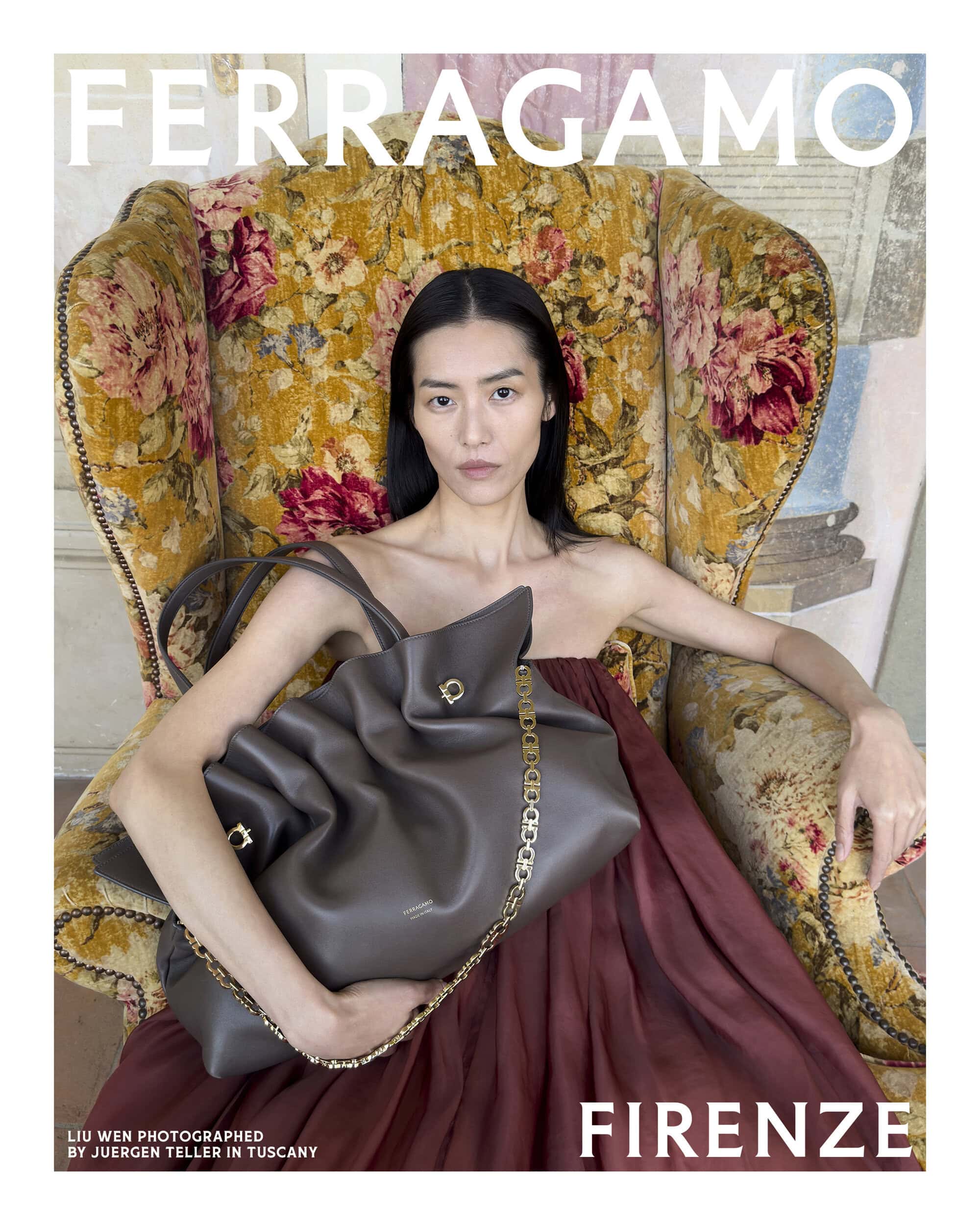 Model Liu Wen holding a large grey leather handbag while seated in an ornate floral armchair for Ferragamo