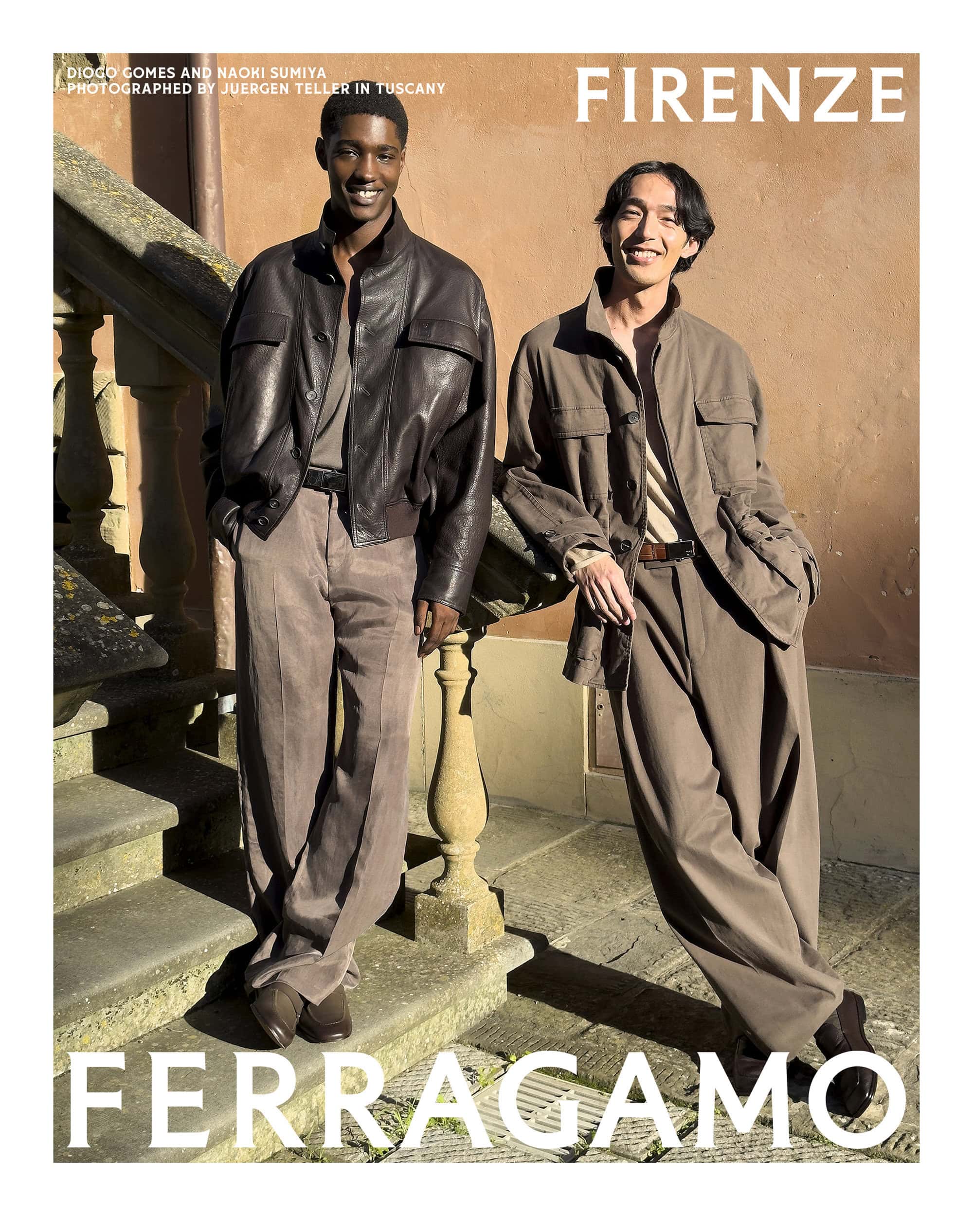 Two male models posing outdoors in autumn style apparel on stone steps against a warm plaster wall
