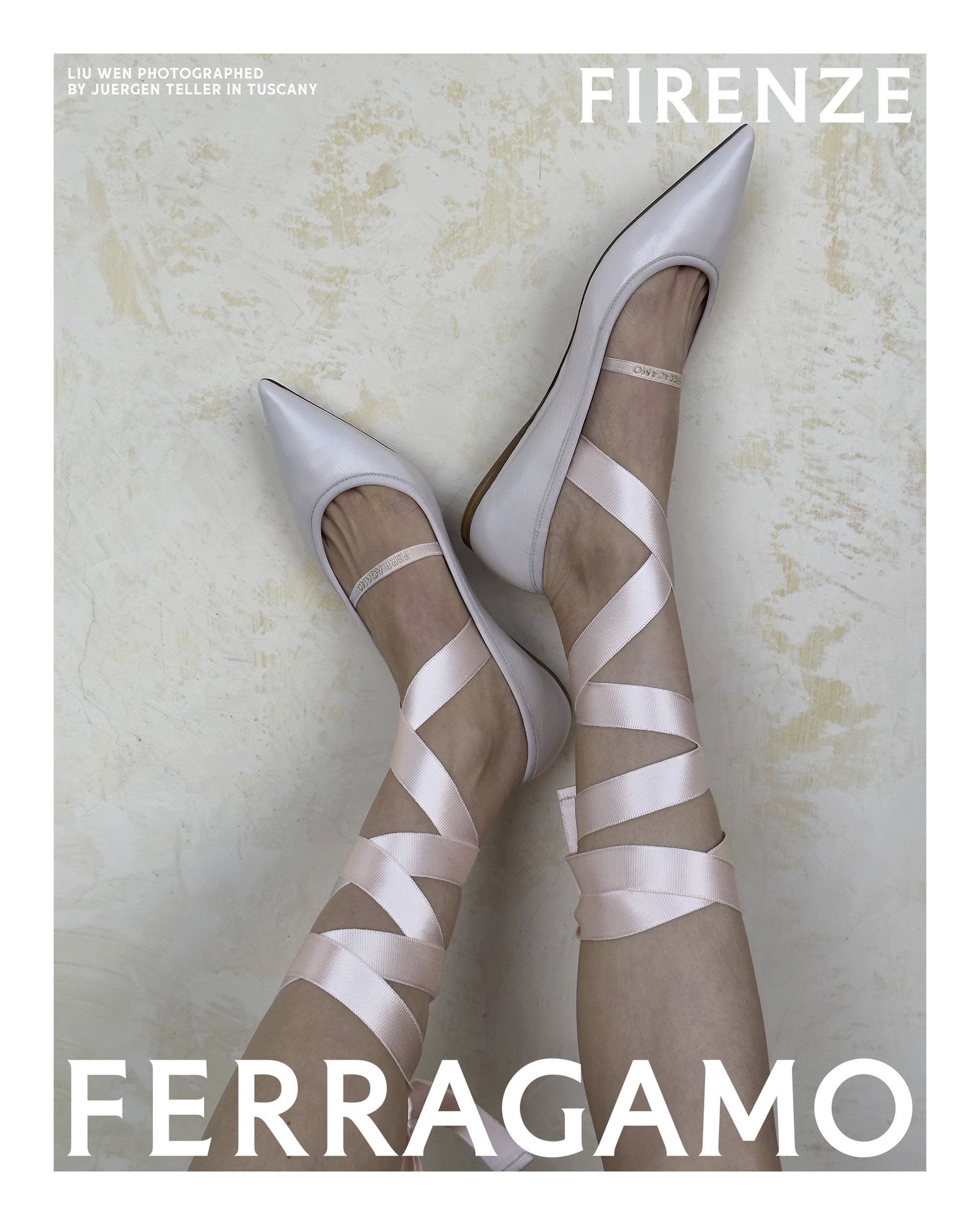 Close-up of legs wearing pale pointed flats with crisscrossed satin pink ribbon ties against a mottled wall