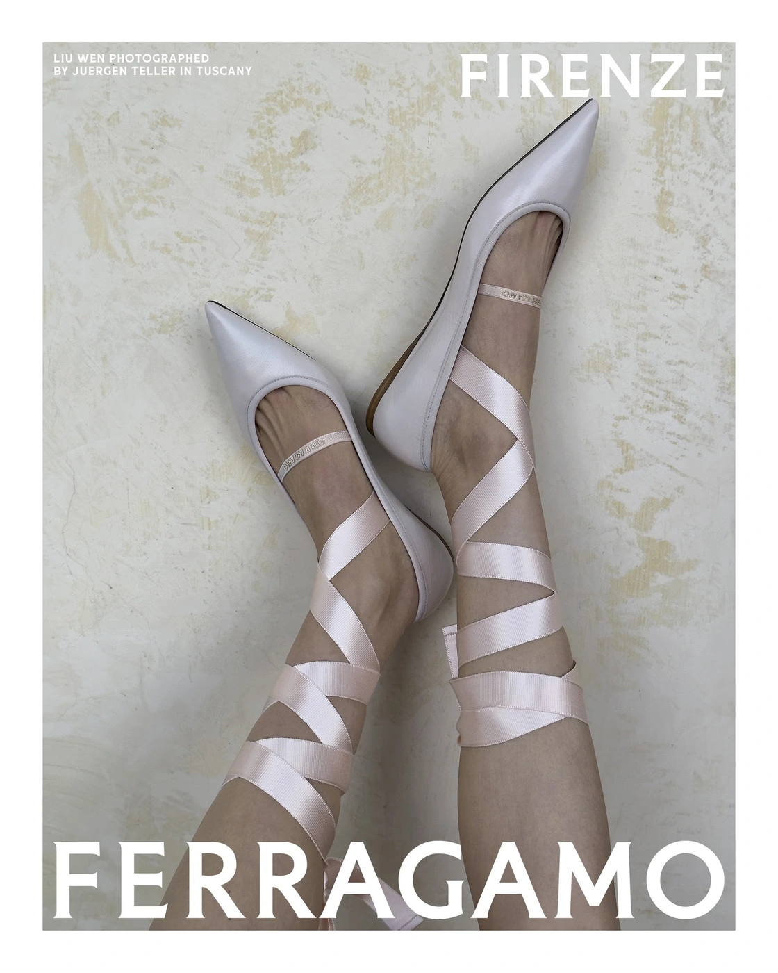 Close-up of legs wearing pale pointed flats with crisscrossed satin pink ribbon ties against a mottled wall