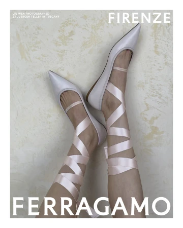 Close-up of legs wearing pale pointed flats with crisscrossed satin pink ribbon ties against a mottled wall