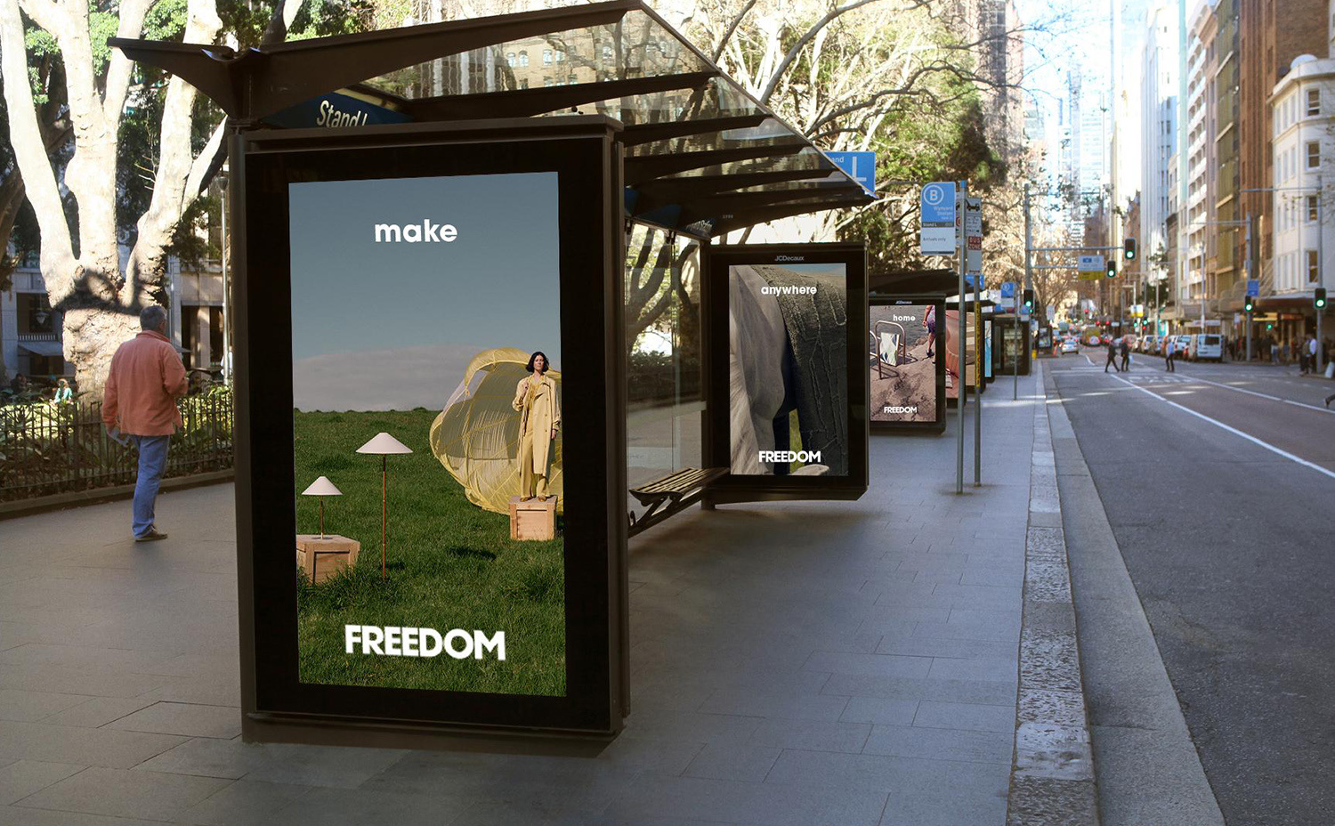 Urban bus stop ad with a woman in a light yellow outfit standing on a crate in a field. 'FREEDOM' brand on the billboard.