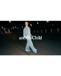 Model in light blue denim jacket and matching wide-leg trousers walking on a dark city street at night.