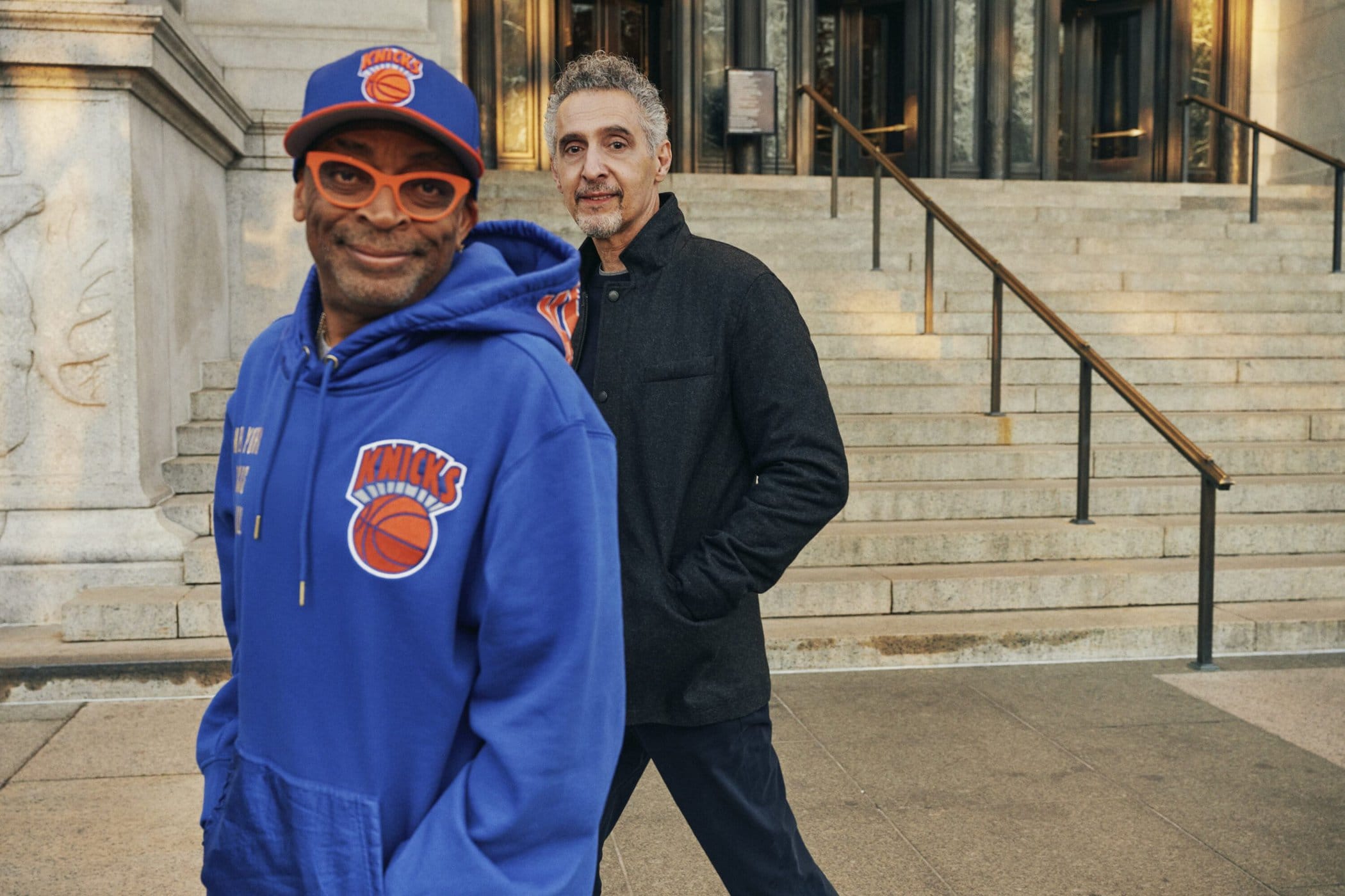 Spike Lee wearing a blue Knicks hoodie and John Turturro standing on steps outside a building for Nordstrom