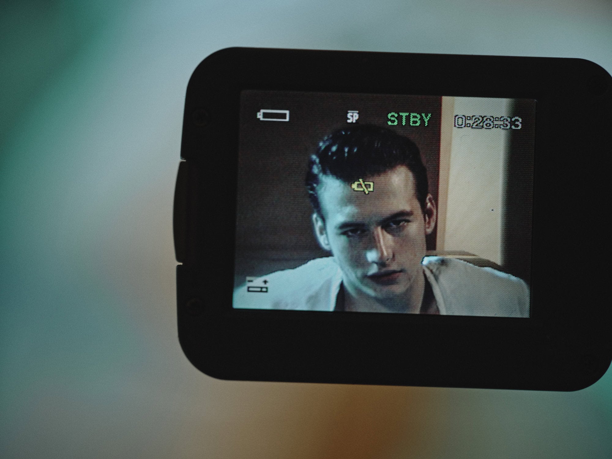 Close-up of a digital camera screen displaying a young man's face on the LCD monitor.