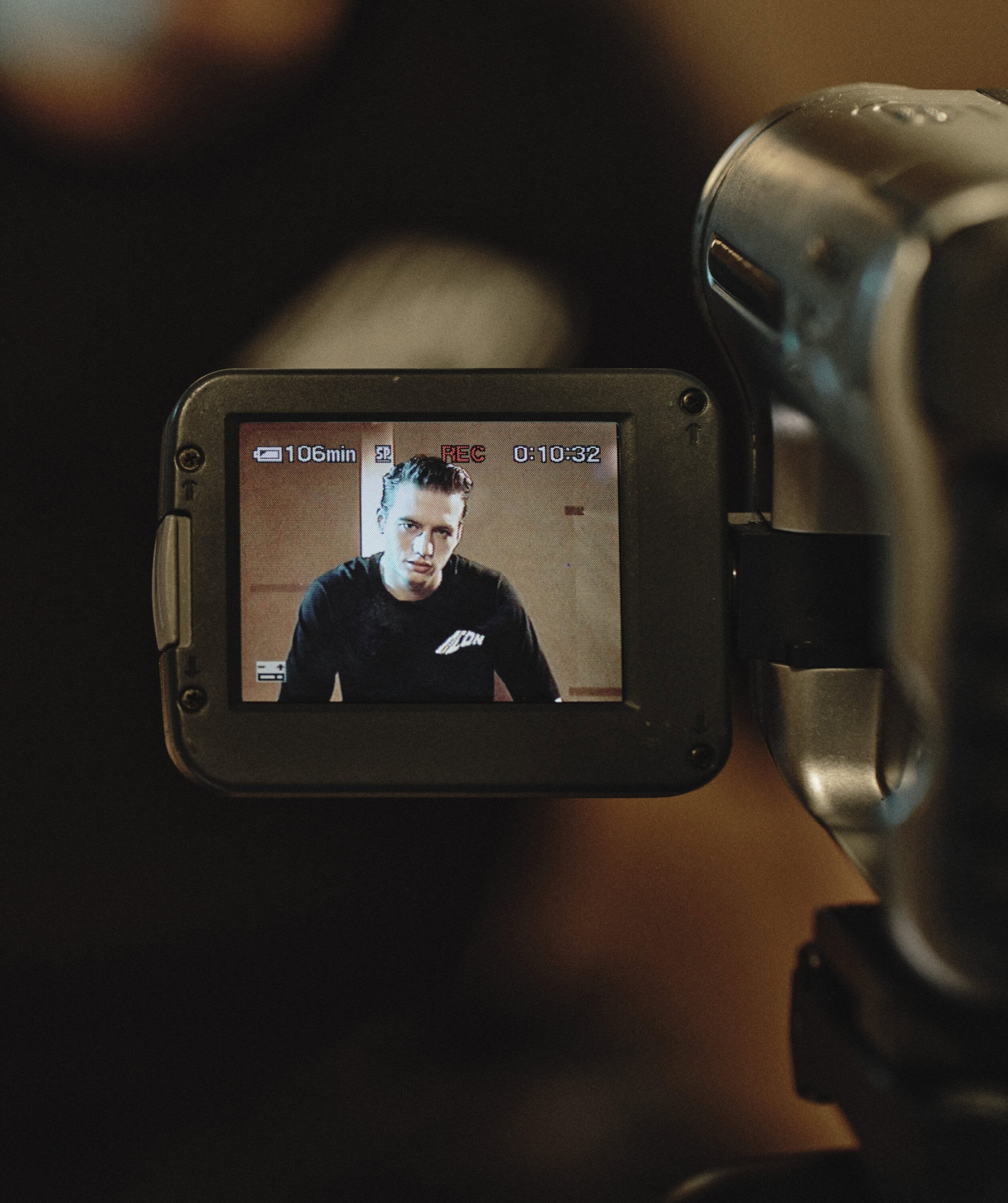 Close-up of a vintage camcorder LCD screen showing a man in a black t-shirt during the Dsquared2 campaign shoot