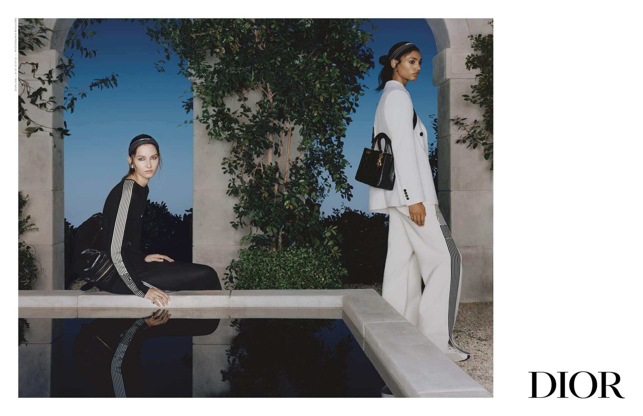 Two models wearing coordinated outfits posed near an outdoor stone pool at twilight for a Dior advertising campaign.