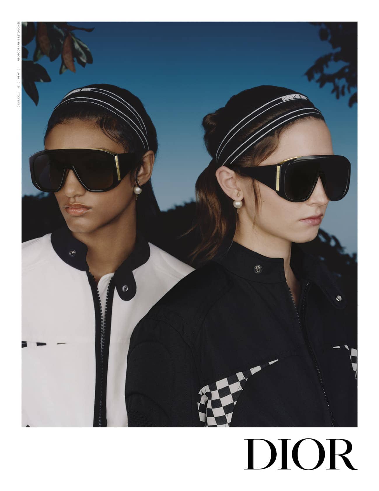 Two female models wearing oversized black sunglasses and headbands against a blue sky background for Dior ad campaign.