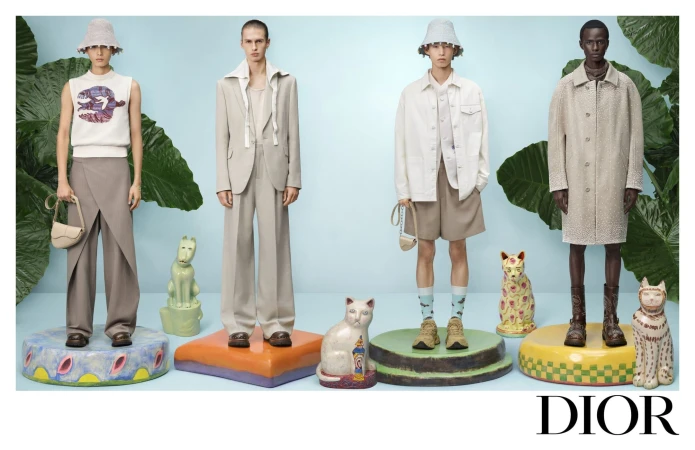 Four male models pose on painted pedestals with ceramic animal sculptures against a light blue backdrop for Dior Spring 2025.