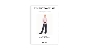 Carey Mulligan featured in Prada Acts Like Prada ad campaign wearing a pink shirt and dark trousers against a white backdrop