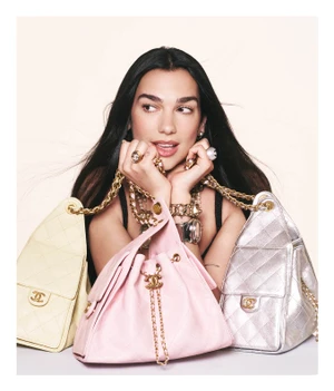 Dua Lipa holding multiple quilted Chanel handbags in an ad campaign by David Sims against a light background