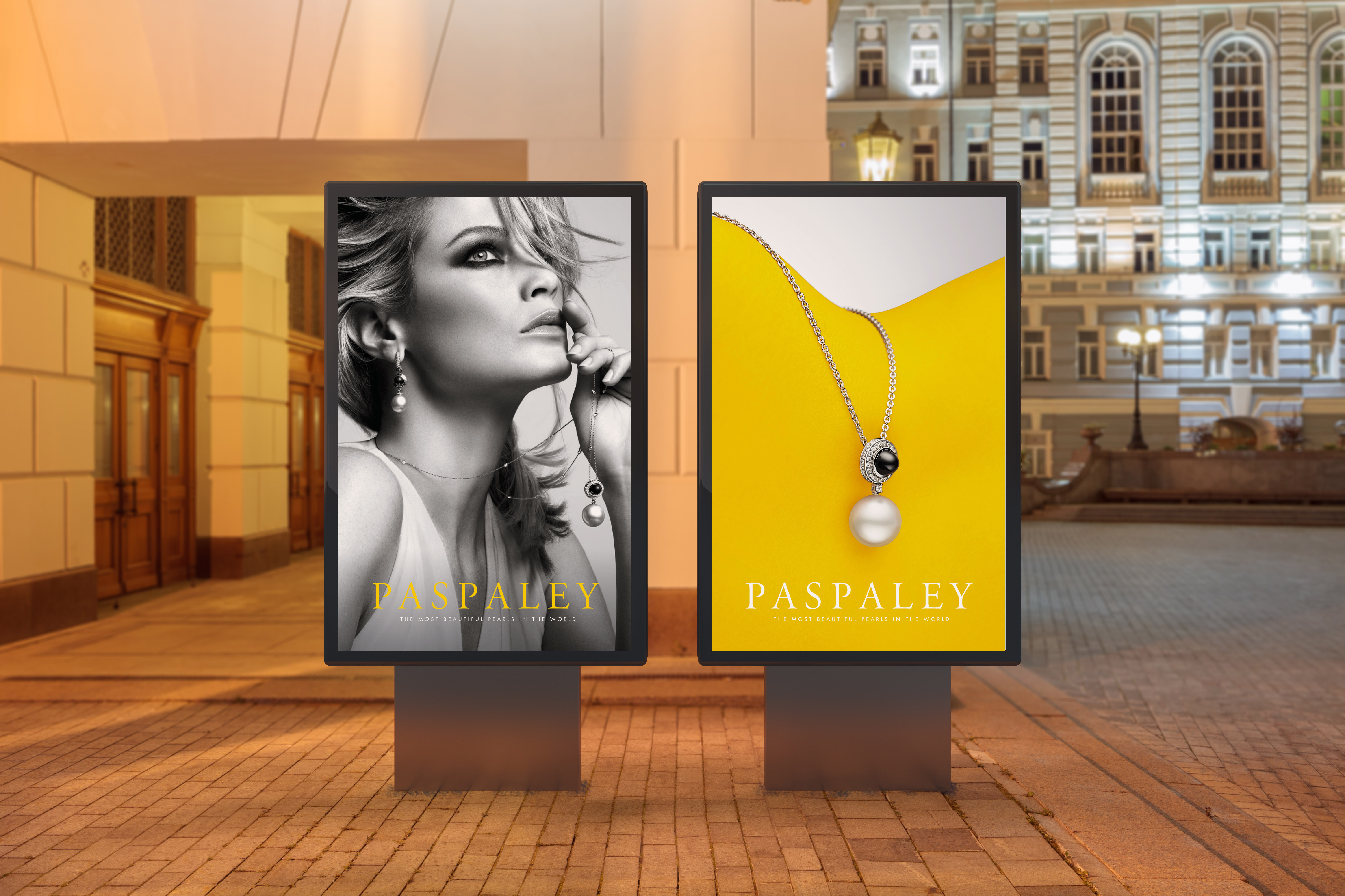 Paspaley jewellery ad displays on two outdoor advertising screens at night, featuring a woman and a necklace with yellow background.