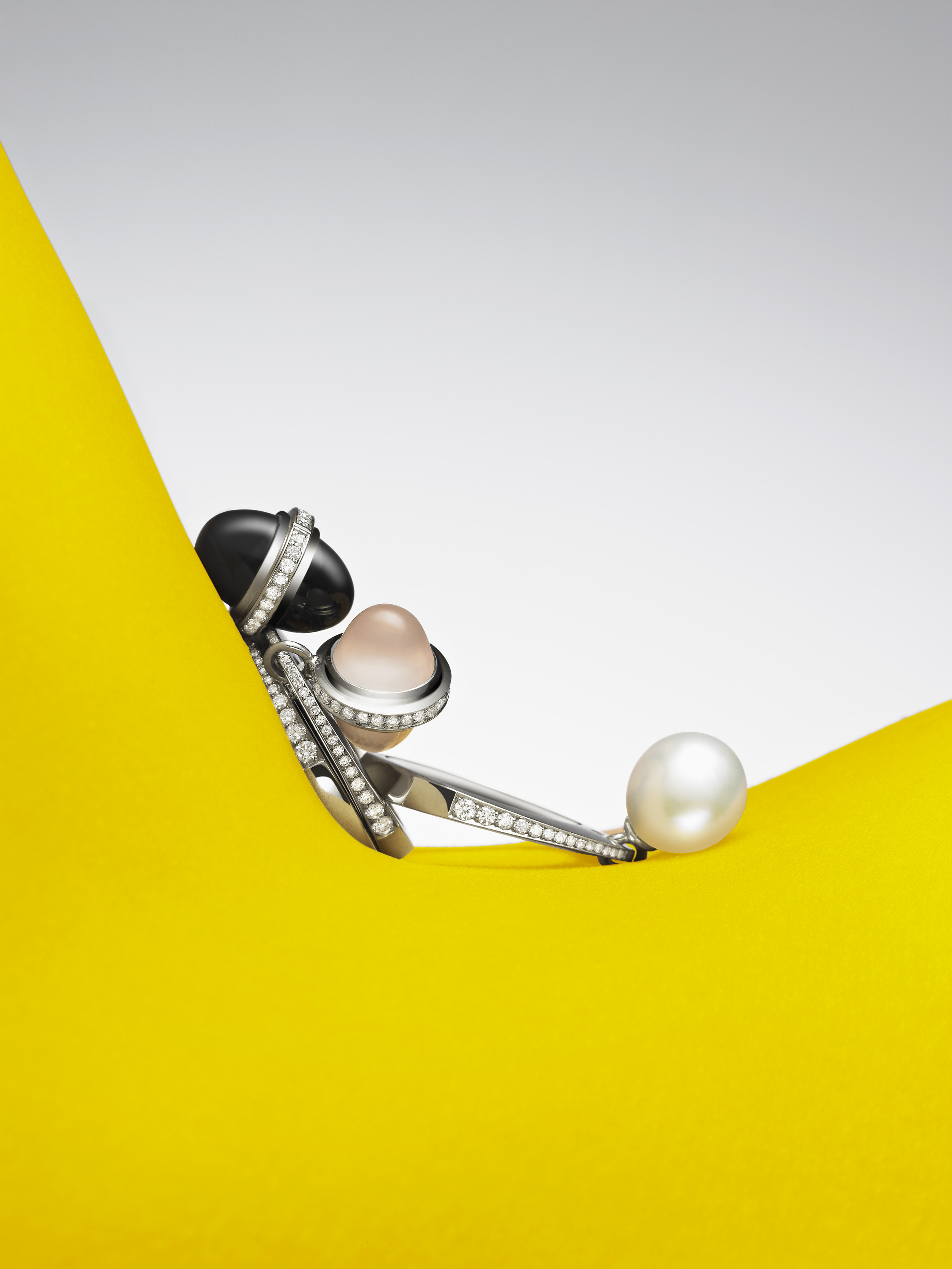 Elegant jewellery featuring lustrous pearls and sparkling diamonds on a vibrant yellow surface with a clean white backdrop.