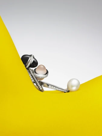 Elegant jewellery featuring lustrous pearls and sparkling diamonds on a vibrant yellow surface with a clean white backdrop. 