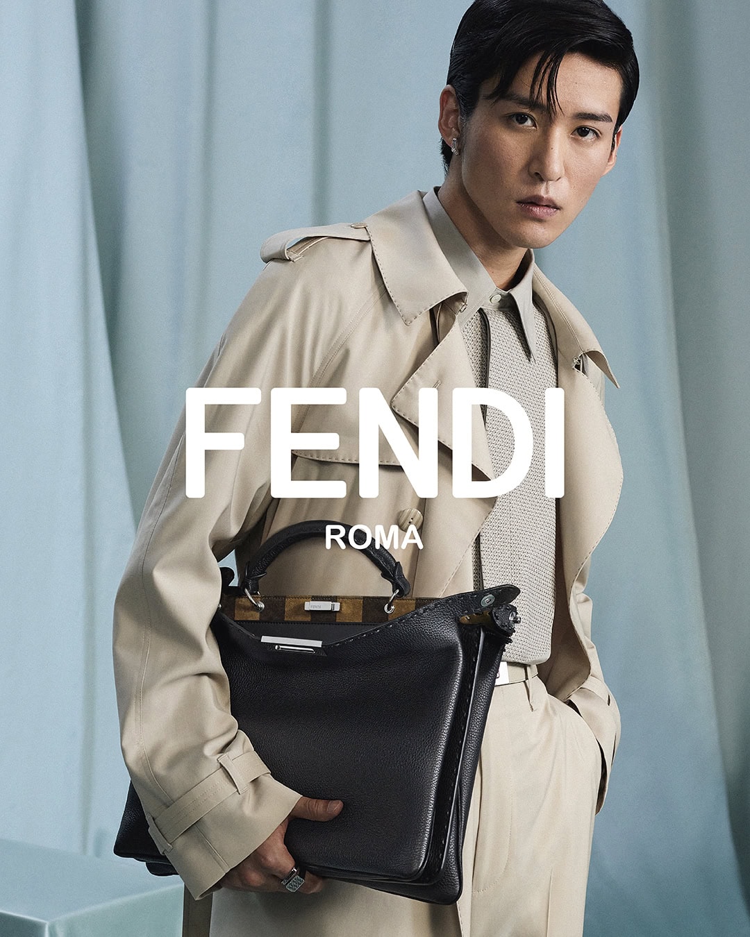 Asian man wearing a beige trench coat holding a black leather handbag for Fendi Spring 2025 campaign